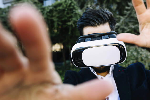 Businessman wearing virtual reality headset stretching hand while standing outdoors model released Symbolfoto XLGF01153
