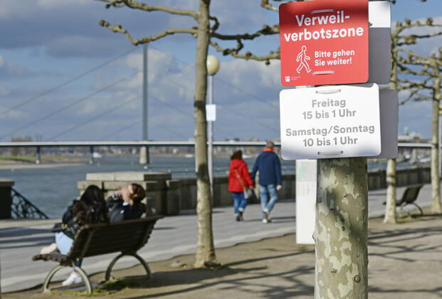 F95 - H96 Düsseldorf, NRW 26.2.2021, Corona, Bitte gehen Sie weiter: Aufgrund der Menschenansammlungen am vergangenen Wochenende hat die Stadt Düsseldorf ein Verweilverbot für die Rheinuferpromenade in der Altstadt festgelegt. Dieses gilt an Freitagen von 15:00 Uhr bis 1:00 Uhr und an Sa So. von 10:00 bis 1:00 Uhr. Noch ist es 14:50 am Freitag und Menschen nutzen die Zeit auf den Parkbänken.