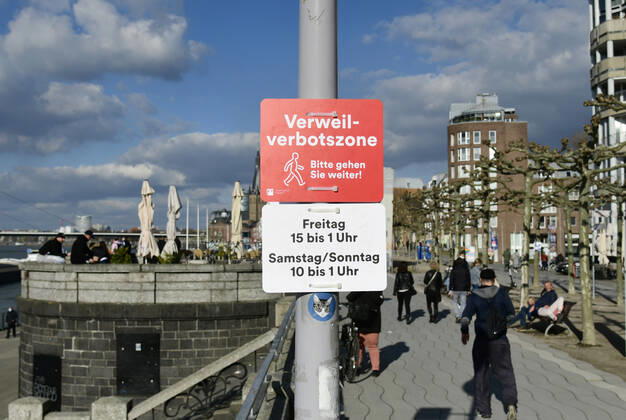 F95 - H96 Düsseldorf, NRW 26.2.2021, Corona, Bitte gehen Sie weiter: Aufgrund der Menschenansammlungen am vergangenen Wochenende hat die Stadt Düsseldorf ein Verweilverbot für die Rheinuferpromenade in der Altstadt festgelegt. Dieses gilt an Freitagen von 15:00 Uhr bis 1:00 Uhr und an Sa So. von 10:00 bis 1:00 Uhr. Noch ist es 14:50 am Freitag und Menschen nutzen die Zeit auf den Parkbänken.