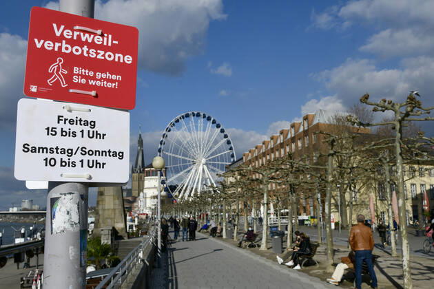 F95 - H96 Düsseldorf, NRW 26.2.2021, Corona, Bitte gehen Sie weiter: Aufgrund der Menschenansammlungen am vergangenen Wochenende hat die Stadt Düsseldorf ein Verweilverbot für die Rheinuferpromenade in der Altstadt festgelegt. Dieses gilt an Freitagen von 15:00 Uhr bis 1:00 Uhr und an Sa So. von 10:00 bis 1:00 Uhr. Noch ist es 14:50 am Freitag und Menschen nutzen die Zeit auf den Parkbänken.