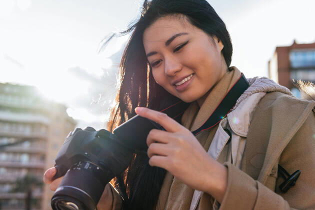 IMAGO Creative: Kreative Renaissance -- der junge Entrepreneur Ethnic young happy Asian female photographer shooting photo on professional photo camera on city street Copyright: xDavidxMunozx Model Released