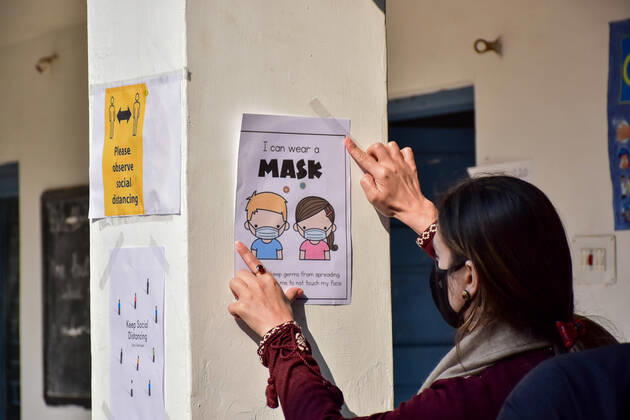 March 1, 2021, Srinagar, India: A staff member pastes a poster of Covid-19 precautions inside the school premises as the schools reopened after one year of break due to the coronavirus pandemic in Srinagar..The schools in Kashmir have reopened for students of classes 9 to 12 after being shut down for nearly one year due to the coronavirus pandemic. Even before the Covid-19 forced their closure, the educational institutes remained closed for nearly a year on of the security and communication clampdown following the abrogation of Article 370 on 5 August 2019. Meanwhile, Jammu and Kashmir recorded 97 new Covid-19 cases taking the infection tally to 1,26,383, officials said. Srinagar India - ZUMAs197 20210301_zaa_s197_059 Copyright: xSaqibxMajeedx