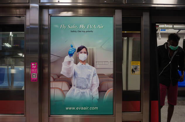 28.02.2021, Singapur, Republik Singapur, Asien - Ein Werbeplakat am Bahnsteig eines MRT U-Bahnhofs wirbt inmitten der anhaltenden Corona-Krise (Covid-19) fuer sichere Flugreisen mit der taiwanesischen Fluggesellschaft EVA AIr.