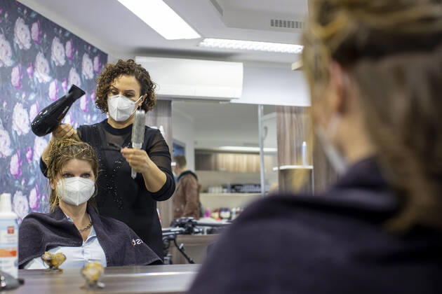 01.03.2021 , DU Duisburg , Friseure dürfen ab dem 01.03.2021 wieder öffnen , Sadiye Kisin vom Friseursalon Haarscharf in Duisburg - Buchholz hat den ersten Termin in ihrem Salon am Marktplatz um 00:01 Uhr versteigert. SPD-Landtagspolitikerin Sarah Philipp hat mit ihrem Gebot von 500 Euro gewonnen , Kisin verdoppelt den Betrag , insgesamt gehen 1000 Euro an die Kindernothilfe in Duisburg. Friseurin Sadiye Kisin föhnt Sarah Philipp die Haare.
