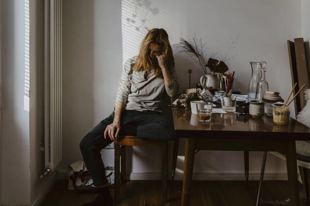 Depressed woman sitting on chair in living room Germany, Berlin, model released, property released Copyright: xMaskotx , MA84850