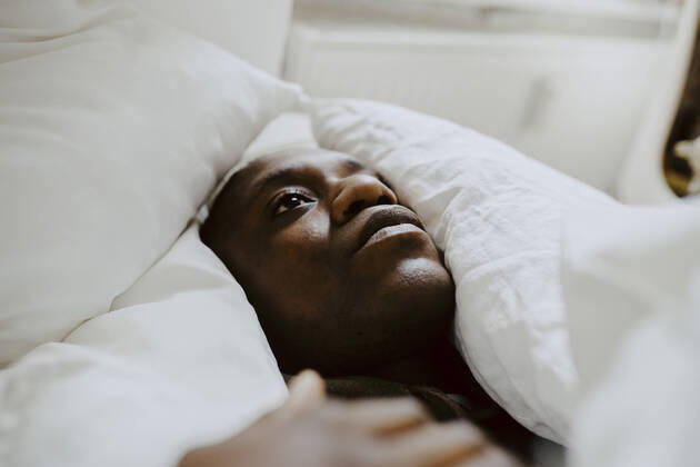 IMAGO Creative: Kulturelle Folgen der Pandemie: Gesundheitsbewußtsein und Alleinsein Depressed man lying amidst pillow in bedroom Germany, Berlin, model released, property released Copyright: xMaskotx , MA84898