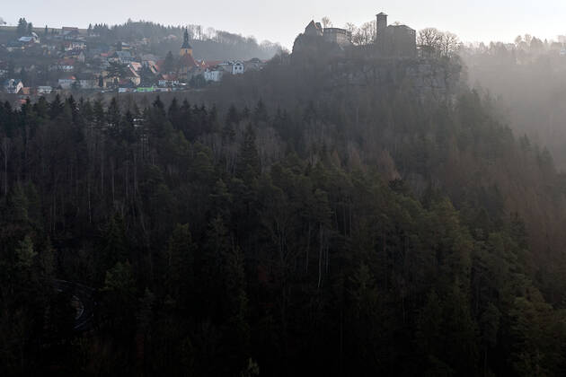 04.03.2021, Deutschland,Sachsen, Sächsische Schweiz, Hohnstein: Blick auf die Burg Hohnstein im Schein der aufgehenden Sonne. Die einzige bis heute erhaltene rechtselbische Burg in der Sächsischen Schweiz wurde vermutlich im 12. Jahrhundert als böhmische Grenzfeste zur Markgrafschaft Meißen gebaut. Heute befinden sich hier unter anderem ein Museum und eine Gedenkstätte. Die Burg liegt malerisch unmittelbar am Nationalpark Sächsische Schweiz auf einem Felssporn über dem Polenztal. Tausende Touristen besuchen Burg und Stadt in der Feriensaison.