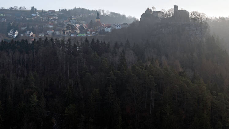 04.03.2021, Deutschland,Sachsen, Sächsische Schweiz, Hohnstein: Blick auf die Burg Hohnstein im Schein der aufgehenden Sonne. Die einzige bis heute erhaltene rechtselbische Burg in der Sächsischen Schweiz wurde vermutlich im 12. Jahrhundert als böhmische Grenzfeste zur Markgrafschaft Meißen gebaut. Heute befinden sich hier unter anderem ein Museum und eine Gedenkstätte. Die Burg liegt malerisch unmittelbar am Nationalpark Sächsische Schweiz auf einem Felssporn über dem Polenztal. Tausende Touristen besuchen Burg und Stadt in der Feriensaison.