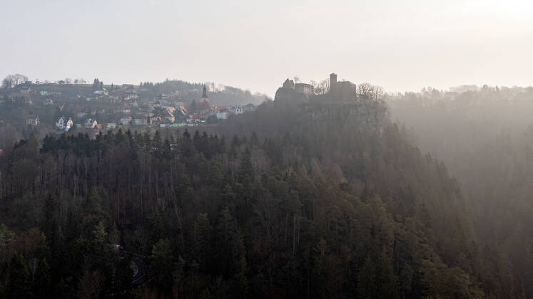 04.03.2021, Deutschland,Sachsen, Sächsische Schweiz, Hohnstein: Blick auf die Burg Hohnstein im Schein der aufgehenden Sonne. Die einzige bis heute erhaltene rechtselbische Burg in der Sächsischen Schweiz wurde vermutlich im 12. Jahrhundert als böhmische Grenzfeste zur Markgrafschaft Meißen gebaut. Heute befinden sich hier unter anderem ein Museum und eine Gedenkstätte. Die Burg liegt malerisch unmittelbar am Nationalpark Sächsische Schweiz auf einem Felssporn über dem Polenztal. Tausende Touristen besuchen Burg und Stadt in der Feriensaison.