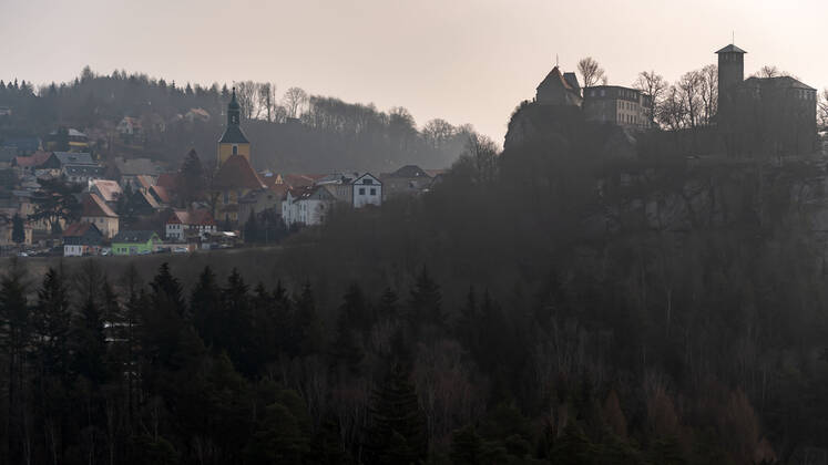 04.03.2021, Deutschland,Sachsen, Sächsische Schweiz, Hohnstein: Blick auf die Burg Hohnstein im Schein der aufgehenden Sonne. Die einzige bis heute erhaltene rechtselbische Burg in der Sächsischen Schweiz wurde vermutlich im 12. Jahrhundert als böhmische Grenzfeste zur Markgrafschaft Meißen gebaut. Heute befinden sich hier unter anderem ein Museum und eine Gedenkstätte. Die Burg liegt malerisch unmittelbar am Nationalpark Sächsische Schweiz auf einem Felssporn über dem Polenztal. Tausende Touristen besuchen Burg und Stadt in der Feriensaison.