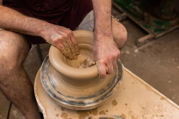 Crop unrecognizable sculptor with equipment giving shape while sculpting with brown clay on throwing wheel, Model released Copyright: xMiguelxVallsx MR
