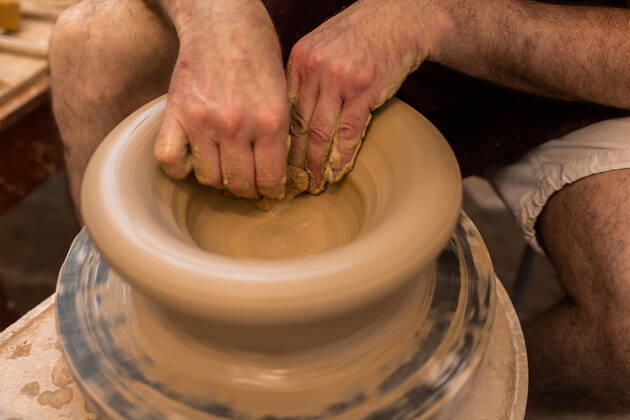 Crop unrecognizable sculptor with equipment giving shape while sculpting with brown clay on throwing wheel, Model released Copyright: xMiguelxVallsx MR