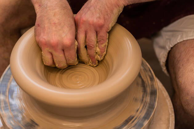 Crop unrecognizable sculptor with equipment giving shape while sculpting with brown clay on throwing wheel, Model released Copyright: xMiguelxVallsx MR