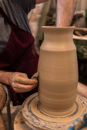 Crop unrecognizable sculptor with equipment giving shape while sculpting with brown clay on throwing wheel, Model released Copyright: xMiguelxVallsx MR