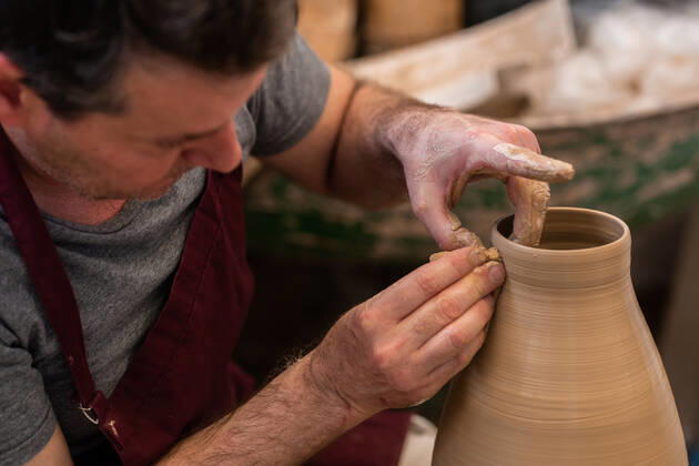 Crop unrecognizable sculptor with equipment giving shape while sculpting with brown clay on throwing wheel, Model released Copyright: xMiguelxVallsx MR