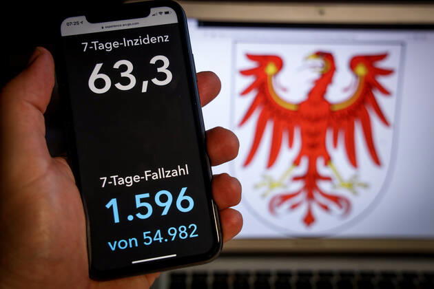Coronavirus in Deutschland - Covid-19-Dashboard des Robert Koch-Institut DEU, Deutschland, Brandenburg, 07.03.2021: Die 7-Tage-Inzidenz für das Bundesland (Fälle letzte 7 Tage 100.000 EW) wird auf einem iPhone angezeigt, im Hintergrund das Landeswappen
