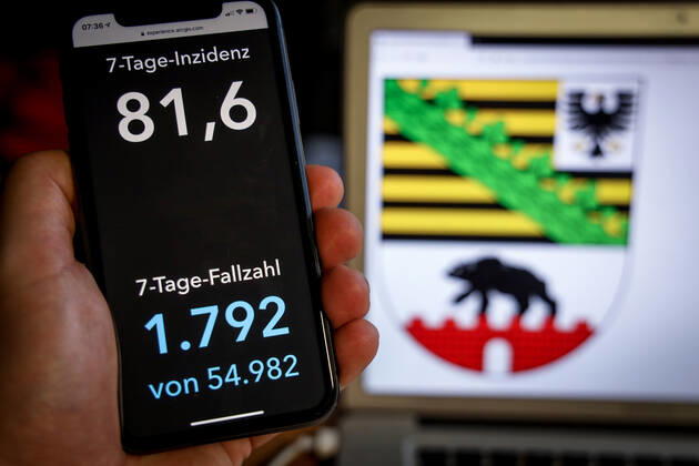 Coronavirus in Deutschland - Covid-19-Dashboard des Robert Koch-Institut DEU, Deutschland, Sachsen-Anhalt, 07.03.2021: Die 7-Tage-Inzidenz für das Bundesland (Fälle letzte 7 Tage 100.000 EW) wird auf einem iPhone angezeigt, im Hintergrund das Landeswappen