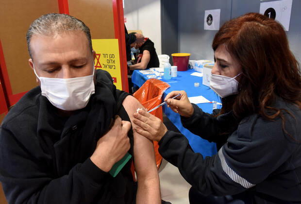 A medic from Israel s Magen David Adam emergency agency inoculates a Palestinian worker with the first dose of the Moderna COVID-19 vaccine at the Lamed Hei Checkpoint between Gush Etzion and Beit Shemesh, on Monday, March 8, 2021. Israel started a two week campaign to vaccine some 100,000 Palestinian workers from the West Bank who hold permits to work in Israel and Jewish settlements. The vaccination campaign is a joint project by the Israeli Heath Ministry, Ministry of Defense, Land Crossing Authority and the Coordination of Government Activities in the Territories.  JER2021030808 DEBBIExHILL