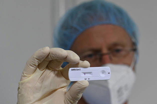09.03.21, Deutschland, Nordrhein-Westfalen, Essen. Coronaschnelltestzentrum in der Grugahalle Essen. Ab dem 08. Maerz koennen sich Bundesbuerger 1x woechentlich kostenlos auf Corona in einem Schnelltestzentrum testen lassen. Blick in eine Schnelltestkabine in der Grugahalle Essen. Arzt zeigt ein negatives Testergenbnis auf einem Teststreifen. Corona Schnelltestzentrum Grugahalle Essen