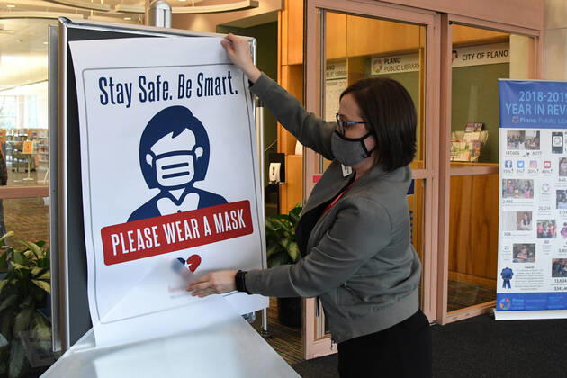 Workers at a public library in Plano, Texas change out signs requiring mask to enter on Tuesday, March 9, 2021 in preparation for changes in the state s mask mandate. Texas Gov. Greg Abbott fully rescinded the statewide mask order and is allowing business to reopen at full capacity effective March 10, 2021 leaving organizations and businesses to determine if they want to require customers to wear masks or not.  DAL2021030902 IANxHALPERIN