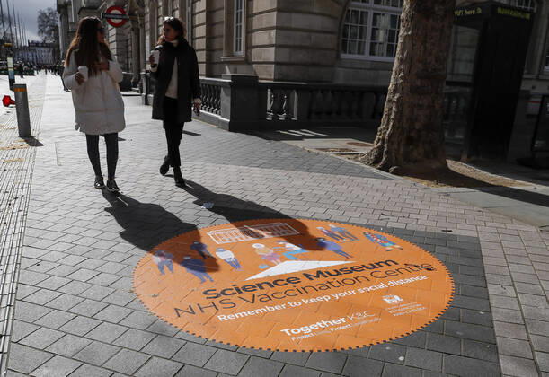 (210312) -- LONDON, March 12, 2021 -- Photo taken on March 11, 2021 shows people walking past a sign on the road outside the NHS COVID-19 Vaccination Centre in the Science Museum in London, Britain. Vaccination centres have opened at Westminster Abbey and Science Museum, according to NHS (National Health Service). ) BRITAIN-LONDON-COVID-19-VACCINATION CENTRES HanxYan 