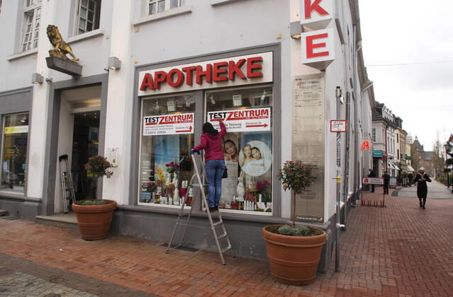 Die Moerser Innenstadt in Corona-Zeiten Blick in die Moerser Fussgängerzone in Corona-Zeiten. Die Moerser Löwen Apotheke bietet kostenlose Corona Teste an. Die Mitarbeiterinnen bringen Wegweiser und Werbeplakate für die Testung an. Mit der Aufschrift: Test-Zentrum - Kostenfreie Testung nach Verordnung des Bundes. Moers Deutschland Nordrhein-Westfalen