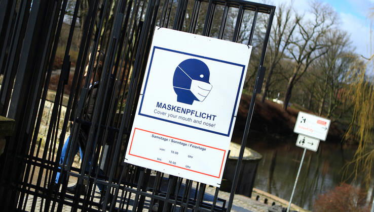 Am Eingang einer Grünanlage in der Hamburger Innenstadt hängen Schilder, die darauf hinweisen, dass in diesem Park am Wochenende und an Feiertagen von 10 bis 18 Uhr Maskenpflicht besteht. Innenstadt Hamburg