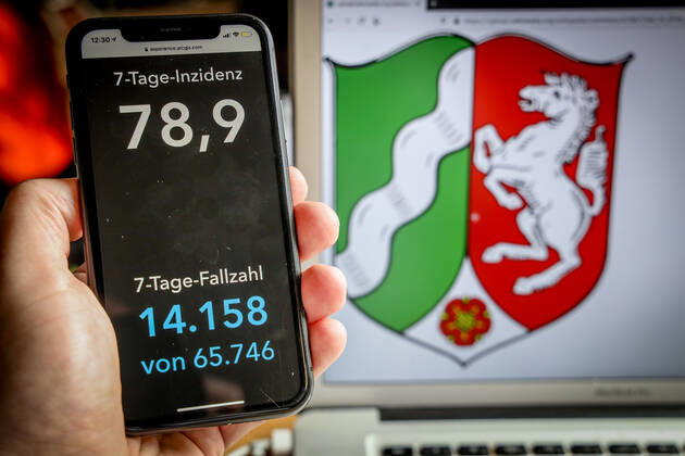 Coronavirus in Deutschland - Covid-19-Dashboard des Robert Koch-Institut DEU, Deutschland, Nordrhein-Westfalen, 14.03.2021: Die 7-Tage-Inzidenz für das Bundesland (Fälle letzte 7 Tage 100.000 EW) wird auf einem iPhone angezeigt, im Hintergrund das Landeswappen