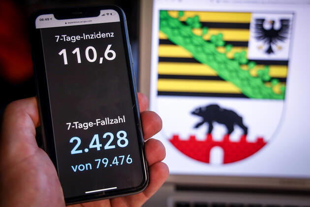 Coronavirus in Deutschland - Covid-19-Dashboard des Robert Koch-Institut DEU, Deutschland, Sachsen-Anhalt, 19.03.2021: Die 7-Tage-Inzidenz für das Bundesland (Fälle letzte 7 Tage 100.000 EW) wird auf einem iPhone angezeigt, im Hintergrund das Landeswappen