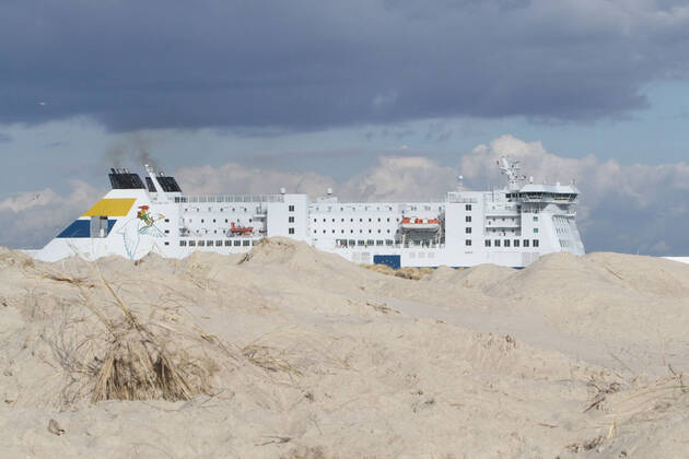 Die RoPax-Fähre Nils Holgersson der deutschen Fährschiffreederei TT-Line läuft am Donnerstag (18.03.2021) in Warnemünde ein während im Vordergrund die Dünen zwischen Strand und Strandpromenade zu sehen sind. Gegenwärtig sind in dem Ostseebad, bedingt durch die Corona – Pandemie, nur wenige Ausflügler zwischen dem Teepott und dem Hotel Neptun unterwegs. Der Fährverkehr zwischen Rostock und dem schwedischen Trelleborg läuft jedoch nach wie vor weiter. Nur jedoch mit wesentlich weniger Passagieren. Ob sich das zu Ostern ändern wird ist bisher völlig unklar. Eine Entscheidung könnte am Montag (22.03.2021) beim Bund-Länder-Gipfel mit der Bundeskanzlerin Angela Merkel und den Länderchefs fallen.