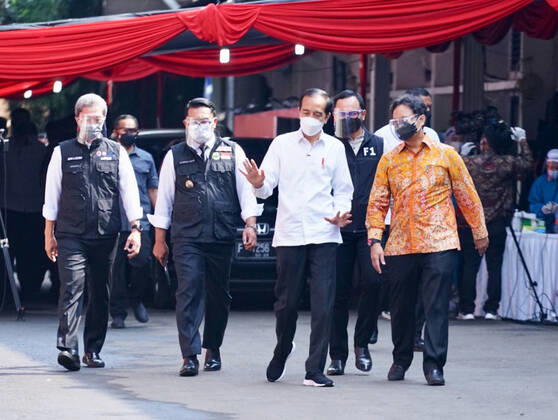President Joko Widodo Reviewing Drive Thru Vaccination In Bogor, Indonesia President Joko Widodo (center) with Health Minister Budi Gunadi Sadikin (right), West Java Governor Ridwan Kamil (left two) and Bogor Mayor Bima Arya (second right), Vice Mayor of Bogor City Dedie Rachim (left) walk while reviewing COVID-19 vaccination at a drive-thru service in Bogor City, West Java, Indonesia on March 19, 2021. President Joko Widodo hopes that other region in Indonesia will be able to imitate the drive thru vaccination model in Bogor City. 