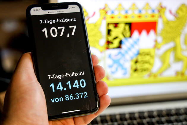 Coronavirus in Deutschland - Covid-19-Dashboard des Robert Koch-Institut DEU, Deutschland, Bayern, 21.03.2021: Die 7-Tage-Inzidenz für das Bundesland (Fälle letzte 7 Tage 100.000 EW) wird auf einem iPhone angezeigt, im Hintergrund das Landeswappen