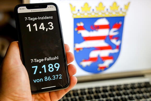 Coronavirus in Deutschland - Covid-19-Dashboard des Robert Koch-Institut DEU, Deutschland, Hessen, 21.03.2021: Die 7-Tage-Inzidenz für das Bundesland (Fälle letzte 7 Tage 100.000 EW) wird auf einem iPhone angezeigt, im Hintergrund das Landeswappen