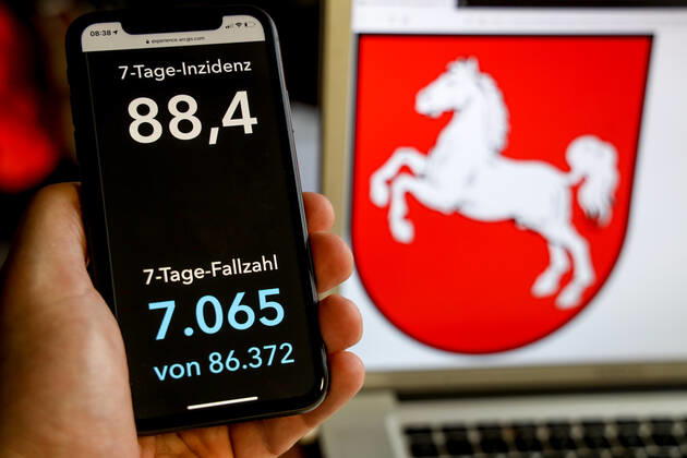 Coronavirus in Deutschland - Covid-19-Dashboard des Robert Koch-Institut DEU, Deutschland, Niedersachsen, 21.03.2021: Die 7-Tage-Inzidenz für das Bundesland (Fälle letzte 7 Tage 100.000 EW) wird auf einem iPhone angezeigt, im Hintergrund das Landeswappen