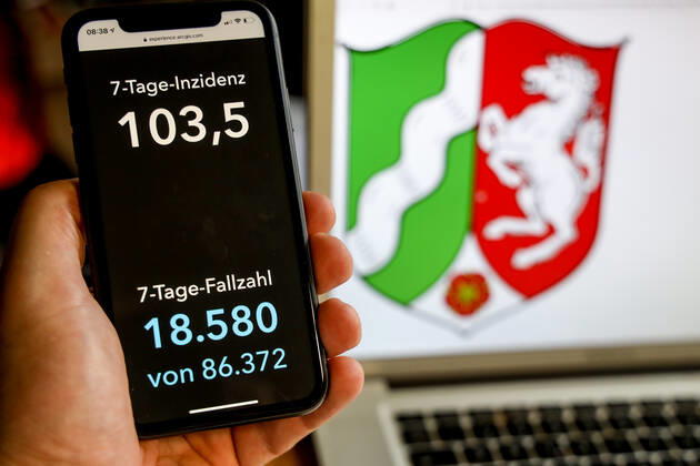 Coronavirus in Deutschland - Covid-19-Dashboard des Robert Koch-Institut DEU, Deutschland, Nordrhein-Westfalen, 21.03.2021: Die 7-Tage-Inzidenz für das Bundesland (Fälle letzte 7 Tage 100.000 EW) wird auf einem iPhone angezeigt, im Hintergrund das Landeswappen