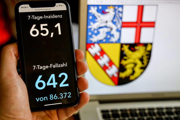 Coronavirus in Deutschland - Covid-19-Dashboard des Robert Koch-Institut DEU, Deutschland, Saarland, 21.03.2021: Die 7-Tage-Inzidenz für das Bundesland (Fälle letzte 7 Tage 100.000 EW) wird auf einem iPhone angezeigt, im Hintergrund das Landeswappen