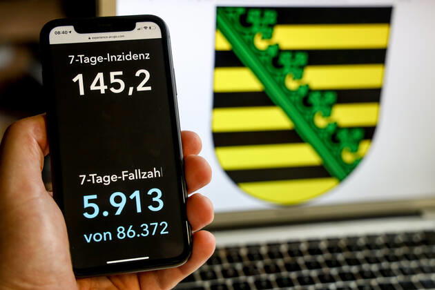 Coronavirus in Deutschland - Covid-19-Dashboard des Robert Koch-Institut DEU, Deutschland, Sachsen, 21.03.2021: Die 7-Tage-Inzidenz für das Bundesland (Fälle letzte 7 Tage 100.000 EW) wird auf einem iPhone angezeigt, im Hintergrund das Landeswappen