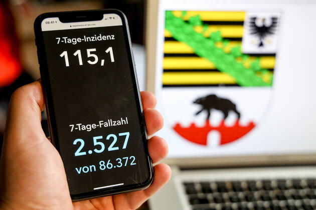 Coronavirus in Deutschland - Covid-19-Dashboard des Robert Koch-Institut DEU, Deutschland, Sachsen-Anhalt, 21.03.2021: Die 7-Tage-Inzidenz für das Bundesland (Fälle letzte 7 Tage 100.000 EW) wird auf einem iPhone angezeigt, im Hintergrund das Landeswappen