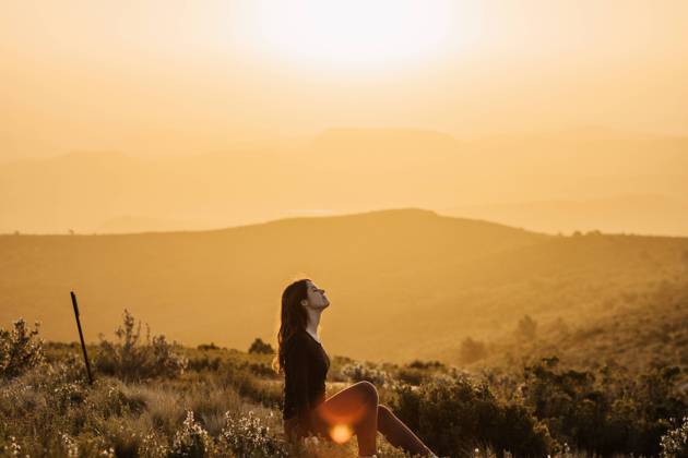 IMAGO Creative: Kulturelle Folgen der Pandemie: Gesundheitsbewu?tsein und Alleinsein Side view of peaceful female traveler sitting on hill with closed eyes and enjoying nature in highlands at sundown, Model released Copyright: xAdrianxVilanovax MR