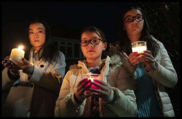 . 23 03 2021. Tonbridge, United Kingdom. Liya Sheehy and her children Lucy (9) and Sophie (11) take part in the beacon of remembrance outside their home in Tonbridge, Kent as part of the National Day of Reflection on the first anniversary of the Covid 19 lockdown in the United Kingdom.  xStephenxLockx xi-Imagesx IIM-22074-0028