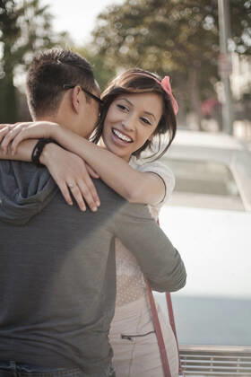 Smiling girlfriend embracing boyfriend standing against car model released Symbolfoto AJOF01247