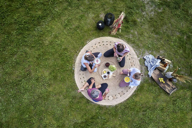 IMAGO Creative: Jahreszeit Frühling, Picknick Caucasian female friends having food while sitting on meadow model released Symbolfoto CVF01664