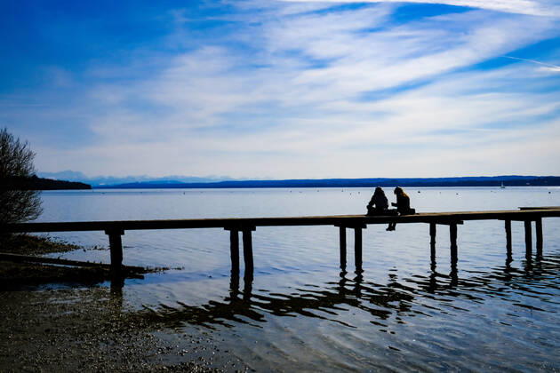 Frühlingswetter am Ammersee 25.03.2021: Ausflügler bei Frühlingswetter am Ufer des Ammersees bei Stegen (Inning am Ammersee; Oberbayern) mit Blick in Richtung Alpen. Inning Bayern Deutschland