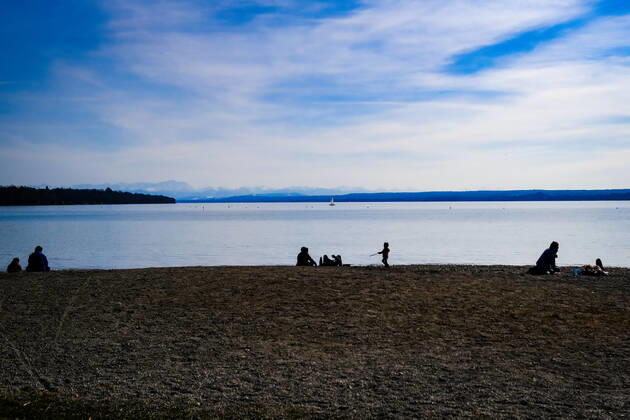 Frühlingswetter am Ammersee 25.03.2021: Ausflügler bei Frühlingswetter am Ufer des Ammersees bei Stegen (Inning am Ammersee; Oberbayern) mit Blick in Richtung Alpen. Inning Bayern Deutschland