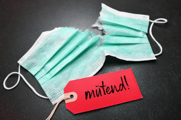 FOTOMONTAGE, Zerrissene OP-Maske mit Etikett und der Aufschrift mÃ¼tend , gemischter Begriff aus wÃ¼tend und mÃ¼de