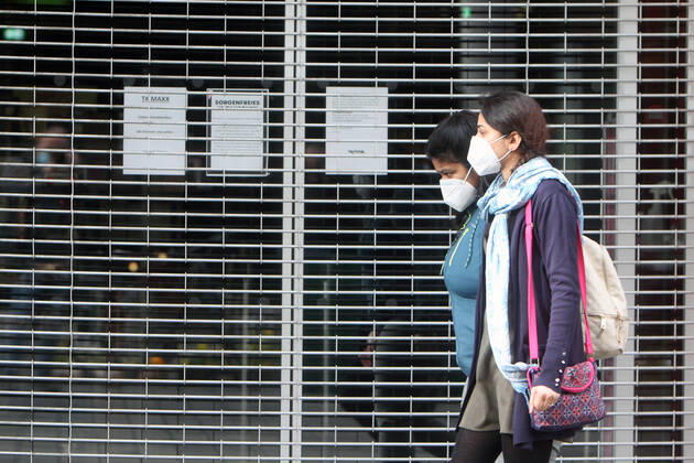 Frauen mit Maske gehen an einem mit Rolltor verschlossenen Geschäft während des Lockdowns in der Einkaufsstraße Fußgängerzone Planken in der Innenstadt von Mannheim vorbei, Baden Württemberg, Deutschland