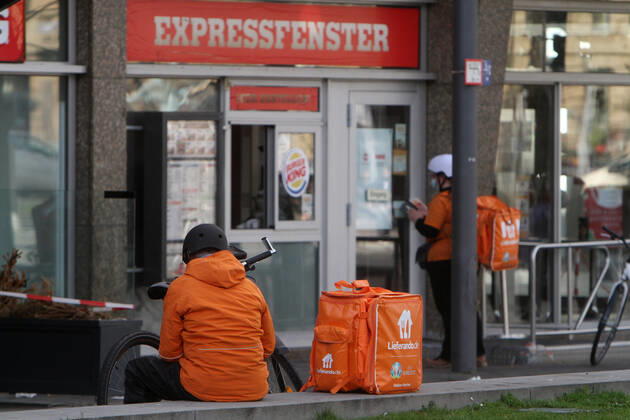 Fahrradkurier vom Internet Portal Lieferando wartet vor einer Burger King Filiale auf Speisen zur Lieferung von Speisen in der Innenstadt von Mannheim, Baden Württemberg, Deutschland