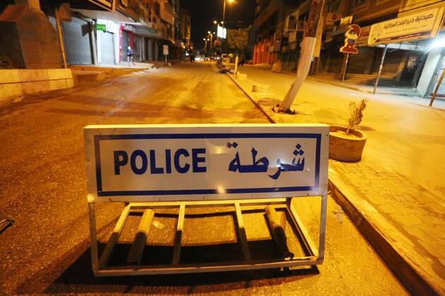 March 27, 2021, Deir Al-Balah, Gaza Strip, Palestinian Territory: Palestinian policemen wear face masks, guard a barrier blocking a road, in Deir Al-Balah in the center of the Gaza Strip, on March 27, 2021, after the Ministry of Interior in Gaza City announced the full lockdown on Saturday all over the Gaza Strip at night-time from 9:00 PM, after the increase in cases infected with Coronavirus Deir Al-Balah Palestinian Territory - ZUMAap3_ 20210327_zaf_ap3_215 Copyright: xAshrafxAmrax