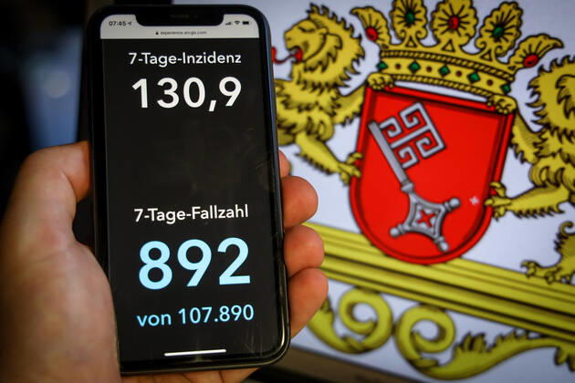 Coronavirus in Deutschland - Covid-19-Dashboard des Robert Koch-Institut DEU, Deutschland, Bremen, 28.03.2021: Die 7-Tage-Inzidenz für das Bundesland (Fälle letzte 7 Tage 100.000 EW) wird auf einem iPhone angezeigt, im Hintergrund das Landeswappen
