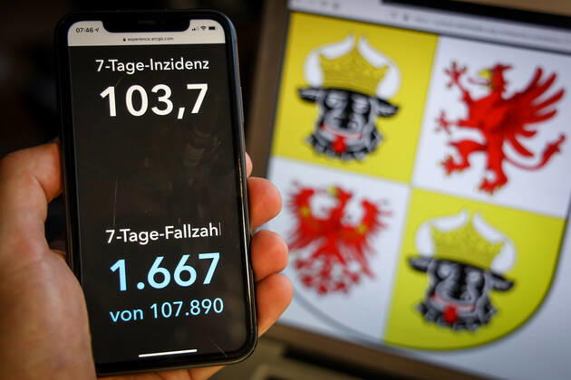 Coronavirus in Deutschland - Covid-19-Dashboard des Robert Koch-Institut DEU, Deutschland, Mecklenburg-Vorpommern, 28.03.2021: Die 7-Tage-Inzidenz für das Bundesland (Fälle letzte 7 Tage 100.000 EW) wird auf einem iPhone angezeigt, im Hintergrund das Landeswappen